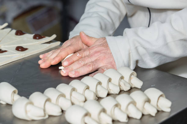 istock Rolling up crescent rolls on the kitchen counter in small business 1552637371