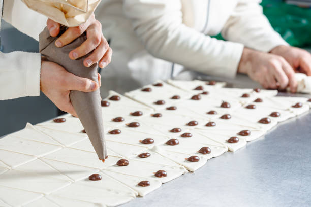 istock Squeezing chocolate cream drops on dough pieces and rolling them up 1552637888