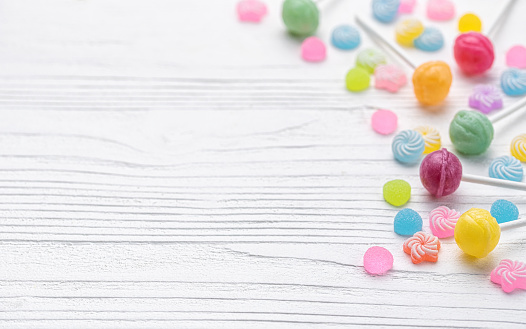 Colorful sweet lollipops and candies over white wooden background.