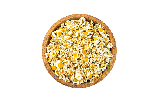 Dried chamomile tea in wooden bowl isolated on white background.dry chamomile. Chamomile tea.