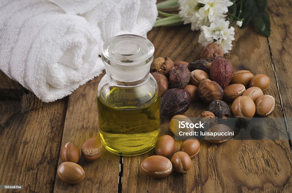 Argan oil with fruits Still life of argan oil with fruit on a natural background. Argan fruits come from Morocco (Africa) and are used as component of many cosmetic products Argan Oil Stock Photo