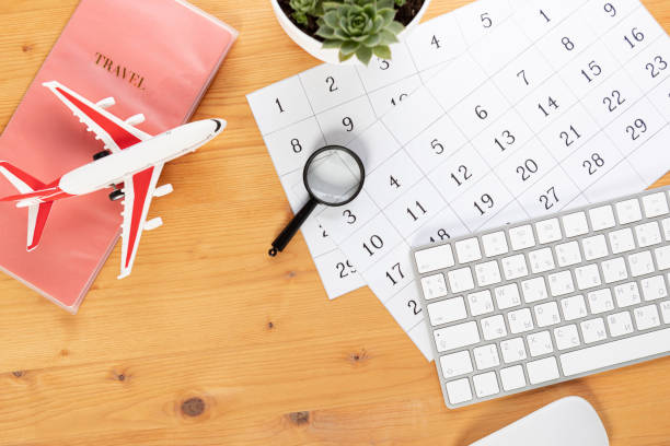 istock Calendar and reminders for work trips, travel and vacations. glider on desktop with airplane and magnifying glass pen, keyboard. mark important plans in a diary at the office desk. 2023 calendar reminder concept. 1552697228