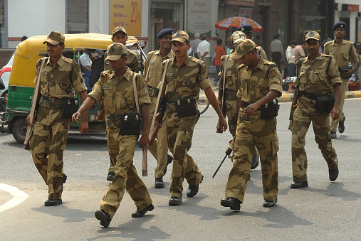 Indian military in camouflage uniforms crosses an intersection on a sunny day in New Delhi, India