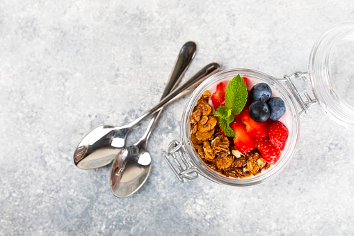 Granola bowl with yogurt and fresh almonds, blueberries, raspberries,peach and strawberries on a  kitchen table.Acai and spirulina bowl.Healthy breakfast concept.copy space.Place for text.