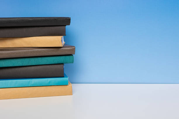 Composition with vintage old hardback books, diary on wooden table and blue background. Books stacking. Back to school. Copy Space. Education background.