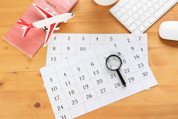 istock Calendar and reminders for work trips, travel and vacations. glider on desktop with airplane and magnifying glass pen, keyboard. mark important plans in a diary at the office desk. 2023 calendar reminder concept. 1552703738