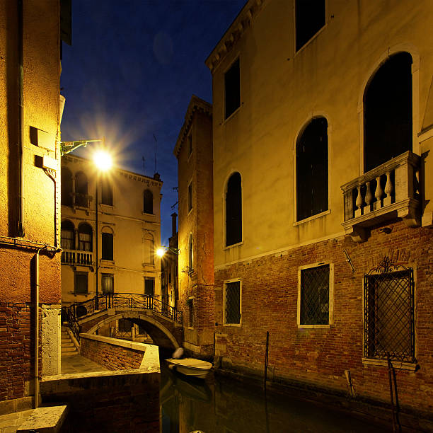 Narrow canal in Venice at midnight. Cool reflections on the water.