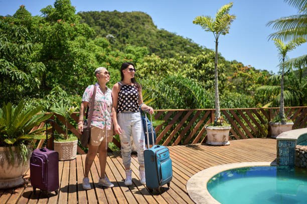 beau couple de lesbiennes arrivant à leur logement de vacances - travel suitcase hawaiian shirt people traveling photos et images de collection