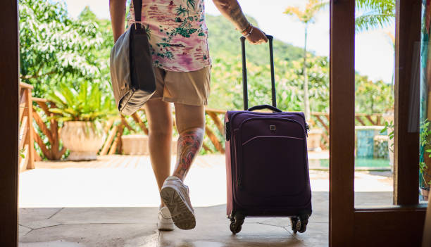 femme avec des bagages quittant son logement de vacances - travel suitcase hawaiian shirt people traveling photos et images de collection