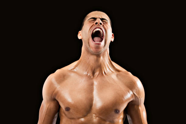 Muscular Arab man screams at the top of his lungs Muscular Arab man screams at the top of his lungs with his eyes closed and extreme tension in his neck and arms. Photographed in front of black background. man muscular chest stock pictures, royalty-free photos & images