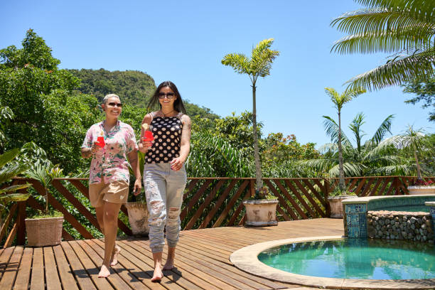 istock Happy lesbian couple with cocktails walking outside on poolside deck 1552742242