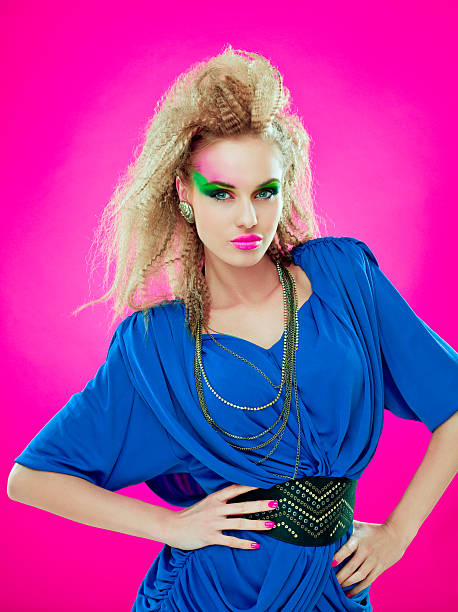 80s style beautiful diva Portrait of 1980s style sensual young woman wearing navy blue dress, looking at the camera. Pink background. vintage hairstyle stock pictures, royalty-free photos & images