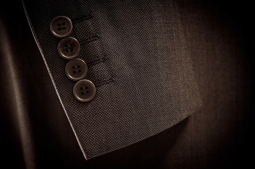 Close-up of suit's sleeve and buttons in brown colour.