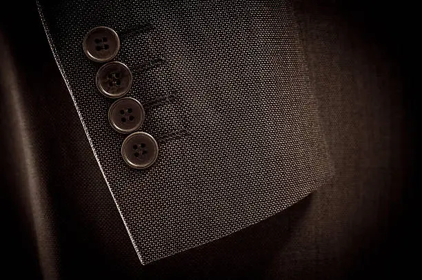 Photo of Close-up of suit's sleeve and buttons in brown colour