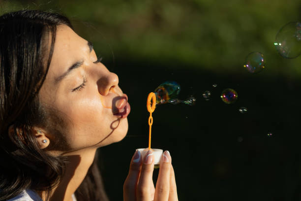 istock Pretty young woman is making soap bubbles on green field in summertime. 1552766059