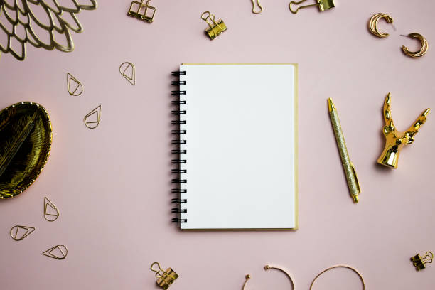 istock A notebook with golden pen and accessories over the pink background. 1552768737