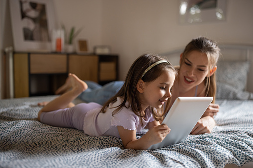 A young Caucasian mother and daughter using a tablet together at home