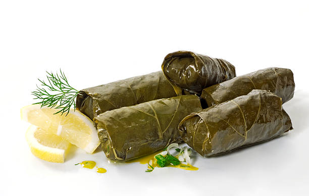 A pile of dolmades with lemon on a white background stock photo