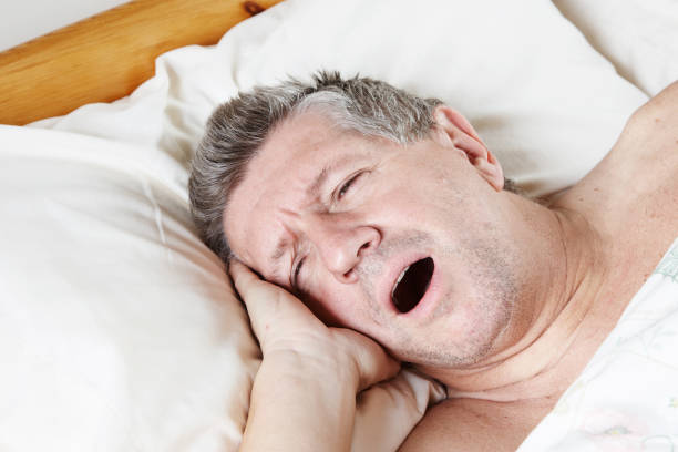 istock Mature man half asleep yawning in bed 155277070
