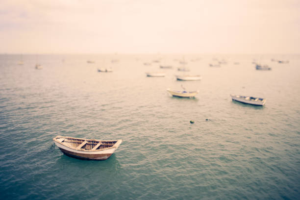 Tilt shift image of a boat floating at anchor in the foreground as other fishing boats fade into the distance in the early morning hours in a sleepy fishing village in Peru.