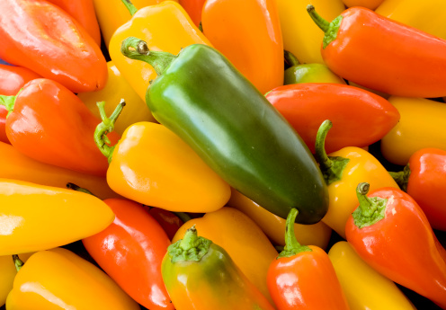Fresh and colorful mini pepper background with a alone jalapeno pepper on top