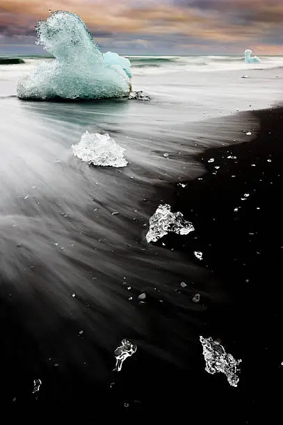 ice sculptures from the famous icelandic glacial lake jökulsarlon lay on the black lava sand beach of the atlantic ocean during the nordic midnight sun