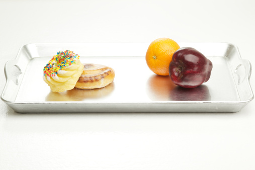 donut, cinnamon roll, apple and orange on a flat surface isolated on silver platter