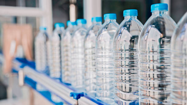 бутылки с водой на автоматизированной конвейерной ленте - water bottle plastic bottle bottling plant стоковые фото и изображения