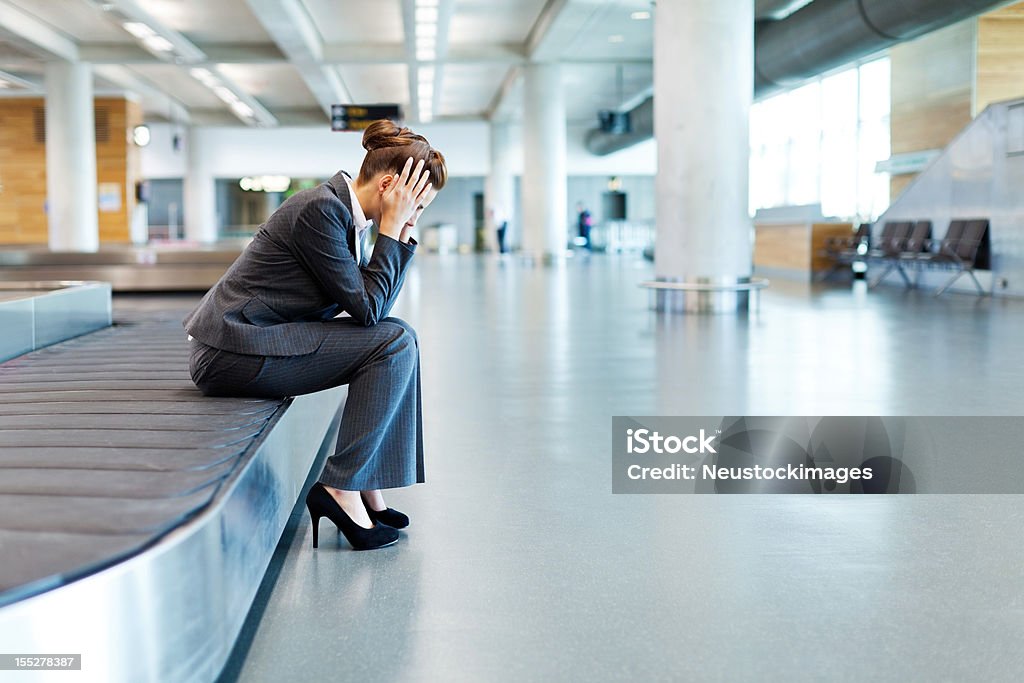 Frustrado empresaria sentado en el área de reclamo de equipaje - Foto de stock de Aeropuerto libre de derechos