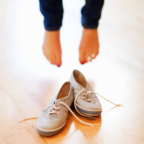 istock Woman Standing Bare Foot In Front Of Canvas Shoes 155278849