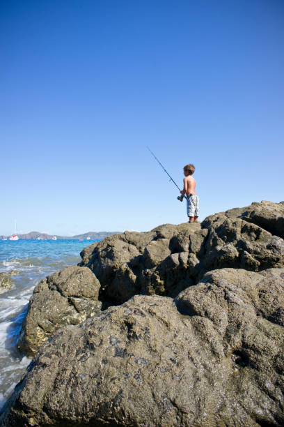 istock Boy fishing off the rocks 155279014