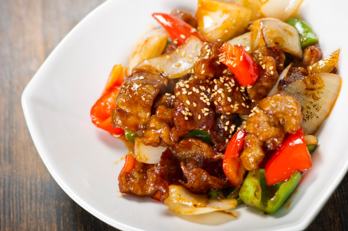 Vibrant dish of sweet and sour pork garnished with toasted sesame seeds
