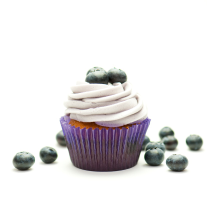 Close-up photo of a blueberry cupcake with fresh berries on white background