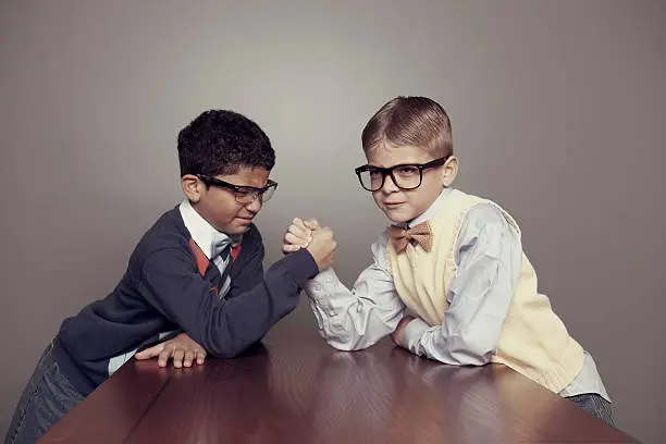 Two young nerds arm wrestle for the top grade in the class.
