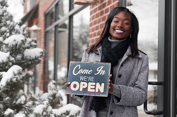 Happy woman holding a Come In We're Open chalk sign stock photo