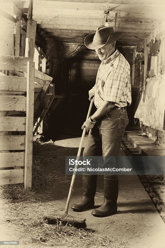 Senior agriculteur nettoyage son barn - Photo de D'autrefois libre de droits