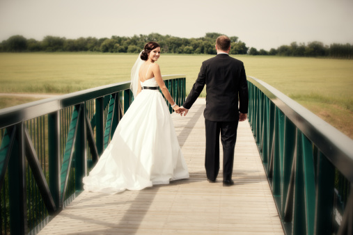 Wedding couple - Groom holding bride's hand outdoors on bridge