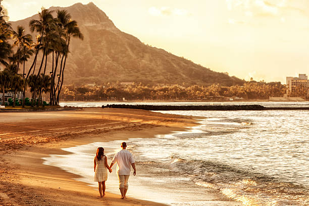 feliz pareja caminando en la playa al atardecer - honeymoon fotografías e imágenes de stock