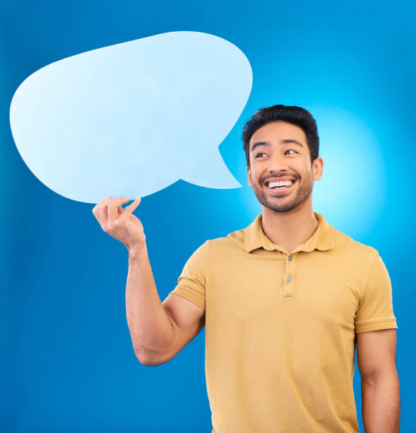 istock Man, speech bubble and thinking in studio with smile for opinion, social media and poster by blue background. Indian guy, student and model with paper, mock up space and cardboard sign for promotion 1552816564