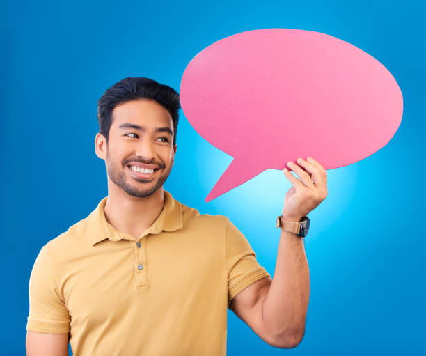 istock Happy, speech bubble and thinking Asian man for communication, feedback or chat. Excited, idea and a person with a board for conversation isolated on a blue background in a studio with space 1552816566