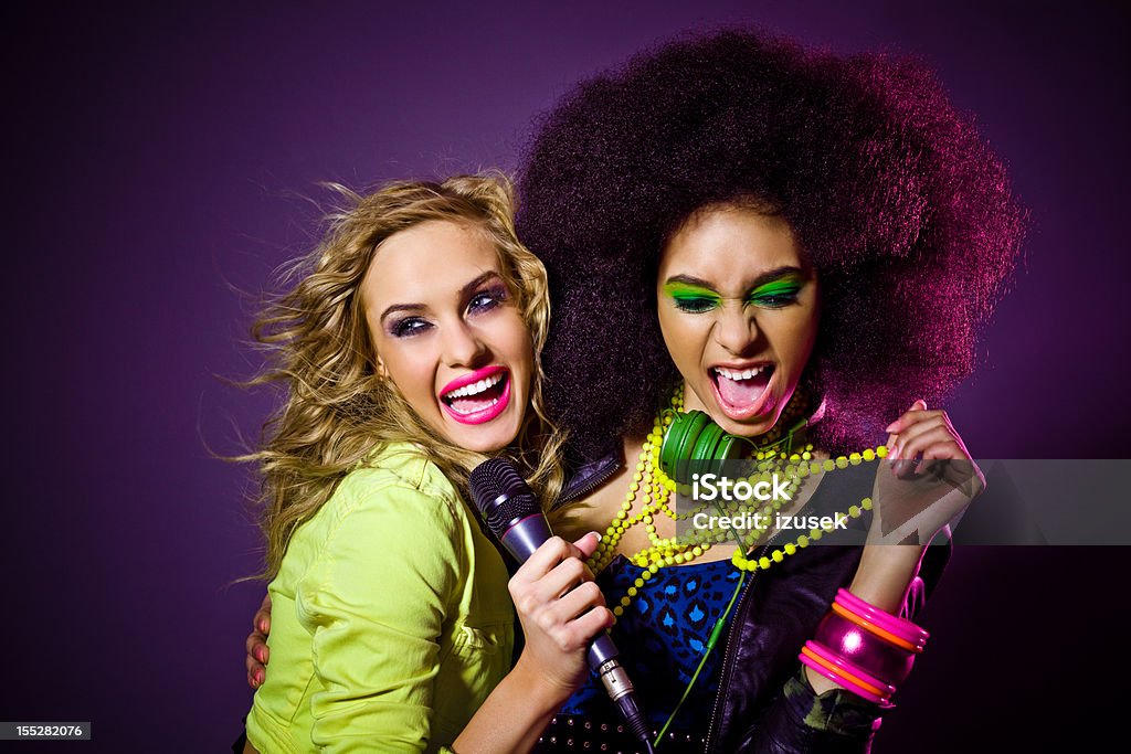 Party Girls Portrait of two beautiful party girls singing. Dark background. 1980-1989 Stock Photo