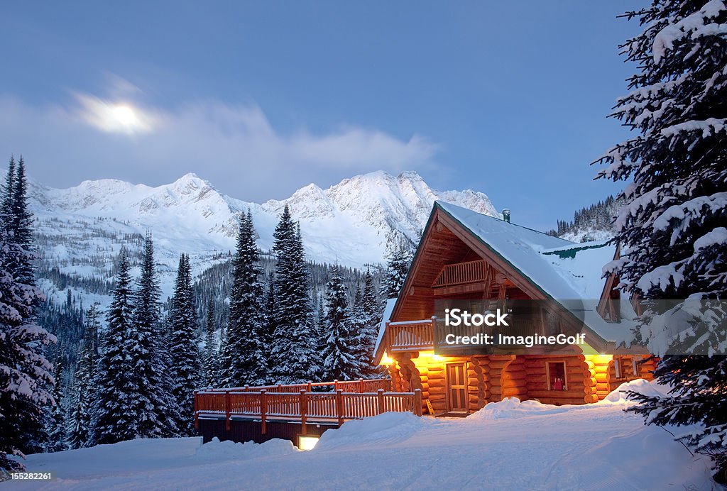 Mountain Lodge in Winter A winter scenic of a rustic, timber-framed lodge in the Canadian backcountry. Horizontal colour image. British Columbia, Canada. Rocky Mountains. Image taken at night with log cabin structure lit with moonlight and starlight.  Log Cabin Stock Photo