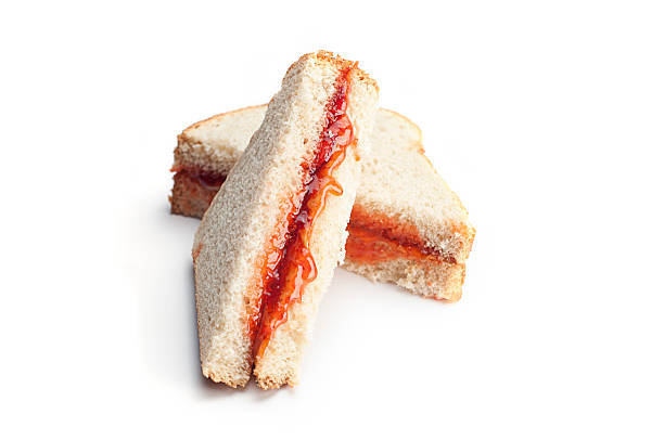 Peanut Butter and Jelly Sandwich Messy peanut butter and jelly sandwich cut in half diagonally and isolated on white. peanut butter and jelly sandwich stock pictures, royalty-free photos & images