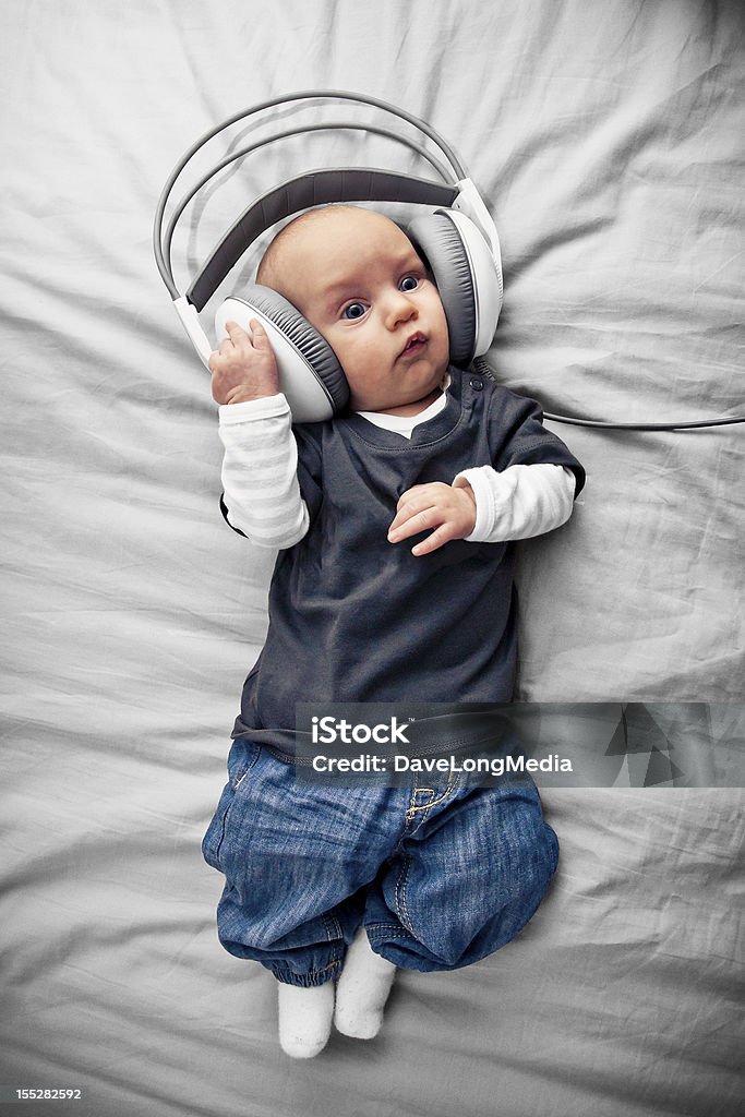 Baby with Headphones Baby boy (3 months old) listening to music in headphones. Baby - Human Age Stock Photo