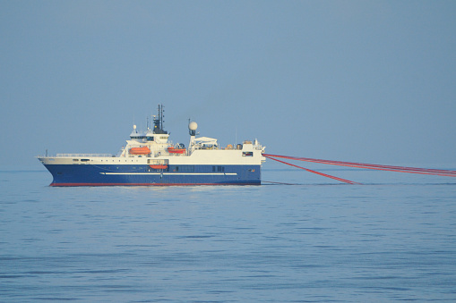 A seismic survey ship pulling survey equipment (streamers). Seismic survey ships map the subsea geology using the seismic sound produced by air guns towed behind the vessel. The information is is used to locate oil and gas deposits.