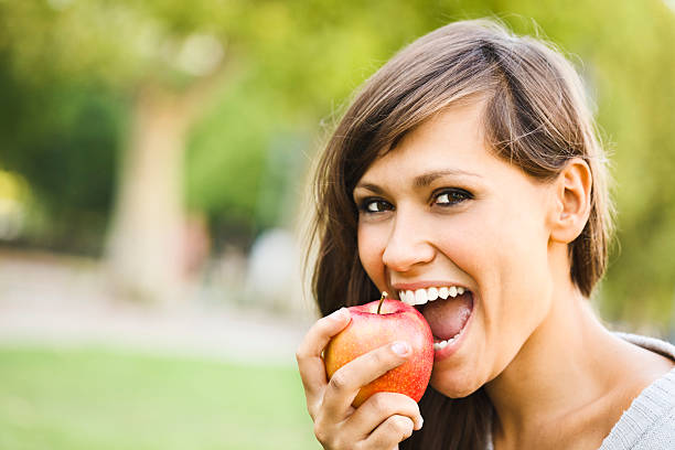 istock Cheerful young woman eating an apple 155283028