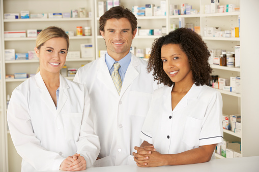 Nurse and pharmacists working in pharmacy smiling at camera