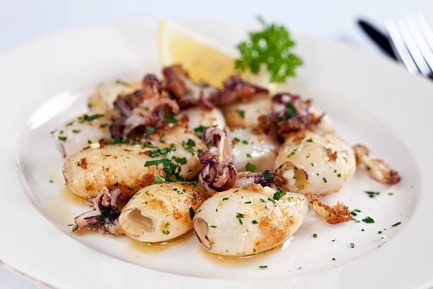 A plate of seafood entree with squid on top stock photo