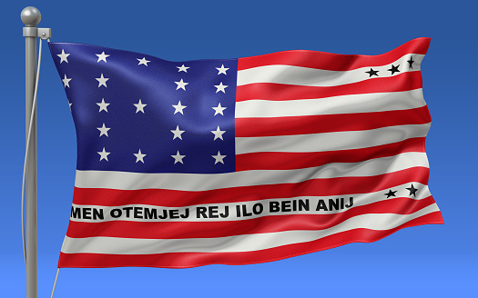 Bikini Atoll flag waving on the flagpole on a sky background