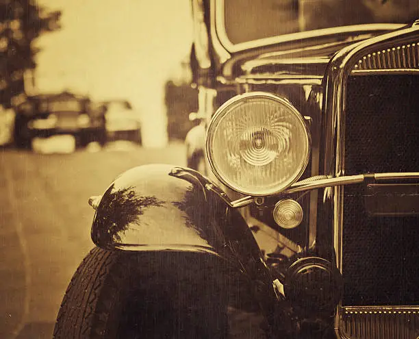 close up detail of the headlamp and grill of an old italian car from the 20s parked, textures overlay - sepia coloring